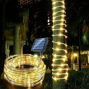 Guirnalda de manguera luminosa solar con panel solar enredada en un árbol de noche