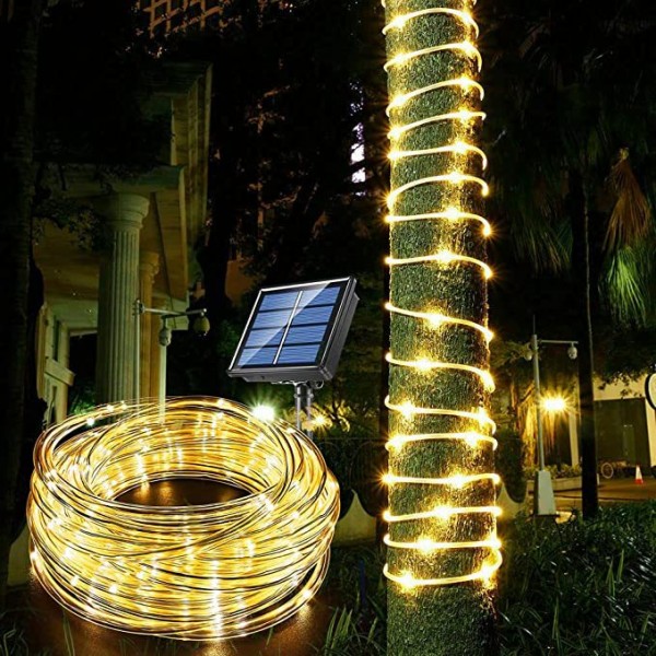 Guirnalda de manguera luminosa solar con panel solar enredada en un árbol de noche